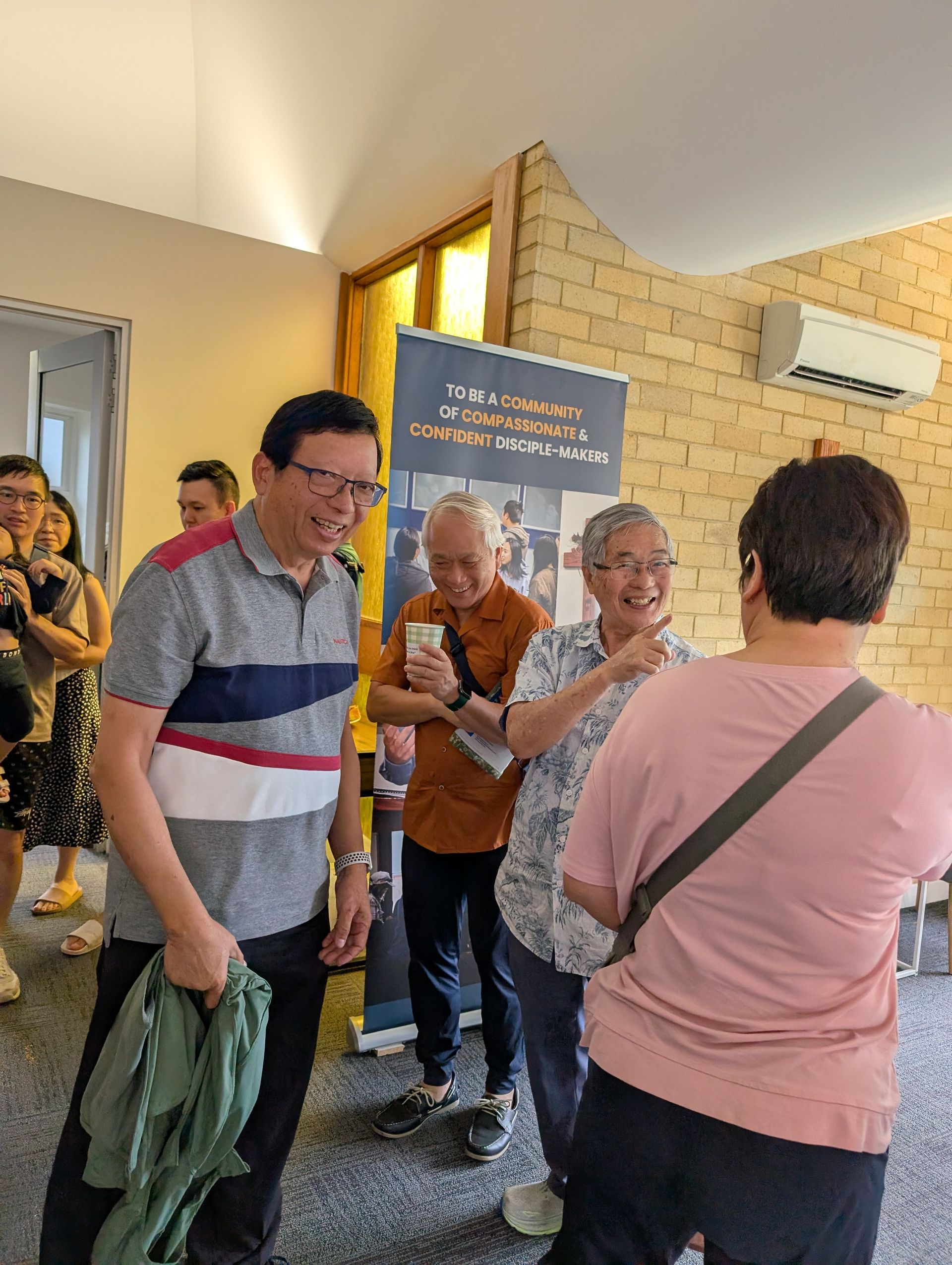 Church members sharing a warm conversation by the vision banner
